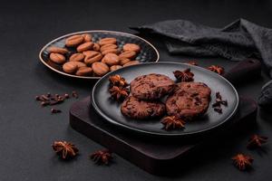 Delicious chocolate cookies with nuts on a black ceramic plate photo