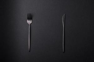 Metal kitchen knife and fork on a dark textured concrete background photo