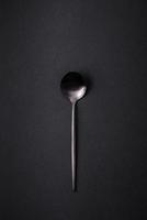 Empty metal spoon on dark textured concrete background photo