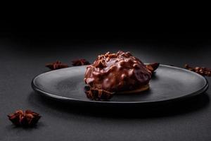 Delicious chocolate tart with nuts on a black ceramic plate photo