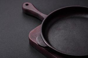 Empty round cast iron skillet on dark textured concrete background photo