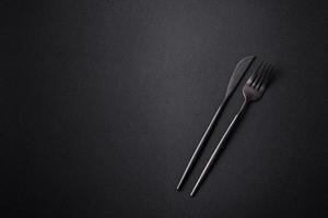 Metal kitchen knife and fork on a dark textured concrete background photo