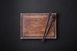 Empty wooden cutting board on dark textured concrete background photo