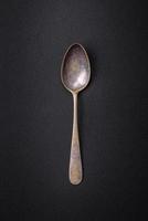 Empty metal spoon on dark textured concrete background photo