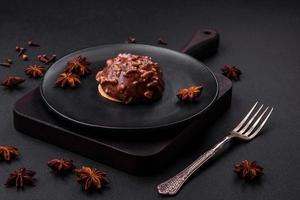 Delicious chocolate tart with nuts on a black ceramic plate photo