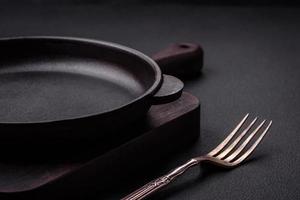 Empty round cast iron skillet on dark textured concrete background photo