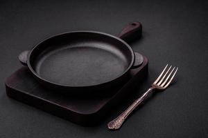 Empty round cast iron skillet on dark textured concrete background photo