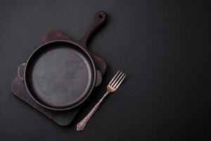 Empty round cast iron skillet on dark textured concrete background photo