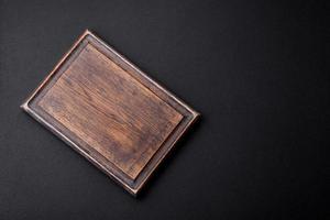 Empty wooden cutting board on dark textured concrete background photo