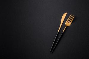 Metal kitchen knife and fork on a dark textured concrete background photo