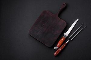 Metal kitchen knife and fork on a dark textured concrete background photo