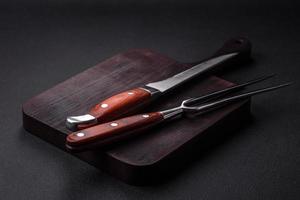 Metal kitchen knife and fork on a dark textured concrete background photo