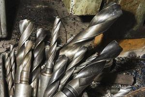 large spiral metal drills in a box in the workshop, drilling machine photo