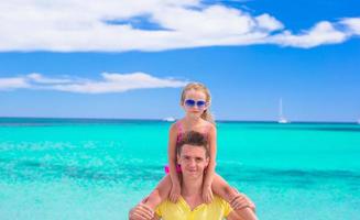 Adorable girl and young dad have fun during tropical beach vacation photo