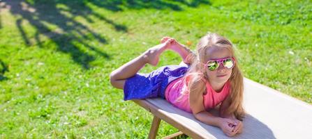 Adorable little girl on beach lounger outdoors photo