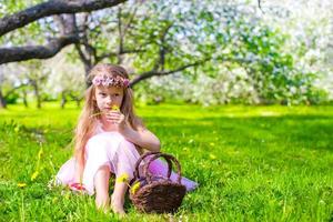 Happy little adorable girl in blossoming apple tree garden photo