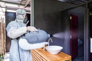 Professional technical man in prevention suit with his sterilizing machine and disinfecting water sprays in toilet or wc area field for purifying coronavirus photo