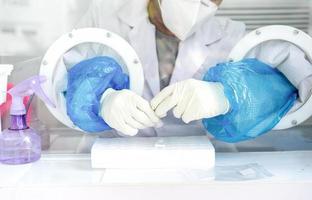 Close up to the rubber gloves on the asian medical staff is processing coronavirus or covid-19 test in the negative room pressure. photo