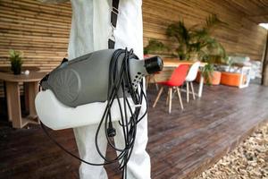 Professional technical man in prevention suit with his sterilizing machine and disinfecting water sprays in the outdoor field for purifying coronavirus photo