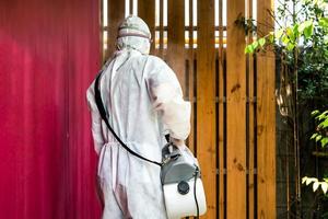 Professional technical man in prevention suit with his sterilizing machine and disinfecting water sprays in the outdoor field for purifying coronavirus COVID19 photo