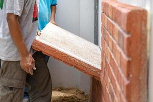 La mano de obra tailandesa está instalada en un tablero de ladrillos de espuma en la pared de cemento foto
