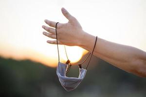 Close up to textile fabric mask is hanged on to man arm with the twilight background. photo