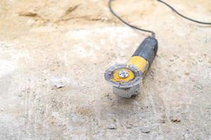 Electric hand held sawing machine is on the sand floor at contruction site. photo