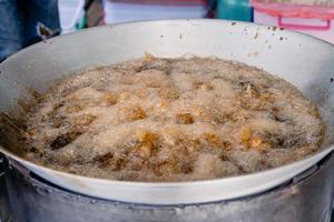 el pollo frito asiático se fríe con aceite de palma en la sartén grande. foto