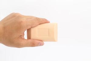 Asian mand hand holds rectangle cream color soap in studio light on white clear background. photo