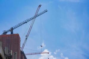 3 grúas giratorias se asientan en el edificio que se está moviendo para construir un edificio incompleto con gancho y cable colgando de él. foto