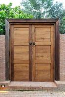 Wooden door and wood frame with the Bronze Knocked Chinese Lion head style on it. This is middle of the brick wall in the garden environment photo