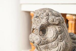 Asian white stone lion statue Chinese vintage style in front of temple on the blur background. photo