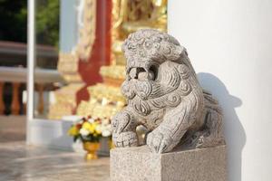 Asian white stone lion statue Chinese vintage style in front of temple on the blur background. photo