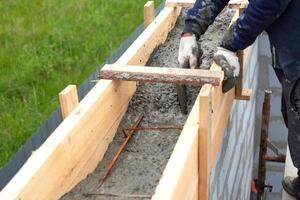 Worker levels concrete in formwork using a trowel photo