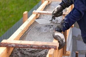 Worker levels concrete in formwork using a trowel photo