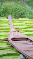 Close up to A wood vintage boat in the Pond of Lotus leaf at out door field. photo