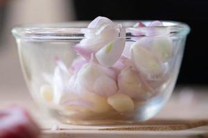 Sliced Shallot and Garlic is put and prepared in Glass Bowl, ready to cook for meal. photo