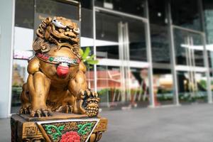 la estatua del león del dios dorado chino es el emperador del ornamento de la estructura zen de asia frente a la puerta para proteger lo malo que entra. foto