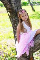 Little adorable girl sitting on blossoming tree in apple garden photo