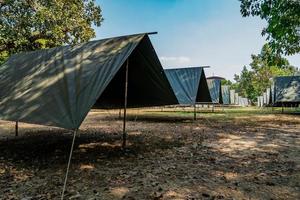 The simple and normal empty Canvas Tents in the row and column on the grass field at outdoor field in afternoon time. photo