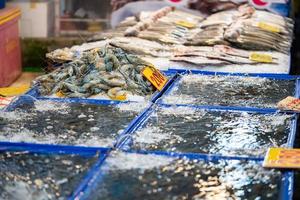 gambas azules frescas nadan en el tanque para vender y cocinar en el mercado local de productos frescos de asia. foto