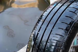 close up to the wet broken tire with the a small nail puncture on it. photo