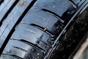 close up to the wet broken tire with the a small nail puncture on it. photo