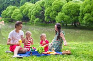 feliz familia joven de picnic al aire libre cerca del lago foto