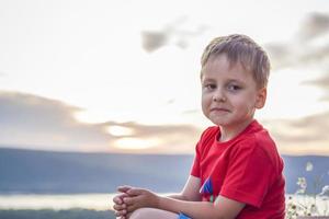 chico lindo con una camiseta roja en el fondo de una impresionante puesta de sol. viaje. el rostro expresa emociones alegres naturales. no escenifican fotos de la naturaleza.