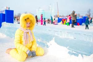 Adorable little girl skating on the ice rink outdoors at warm winter day photo