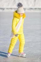 Adorable little girl skating on the ice rink outdoors photo