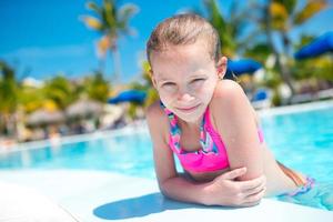 Portrait little girl having fun in outdoor swimming pool photo