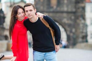 Happy couple walking on the Charles Bridge in Prague. Smiling lovers enjoying cityscape with famous landmarks. photo