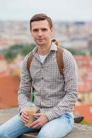 Happy young urban man drinking coffee background european city outdoors photo